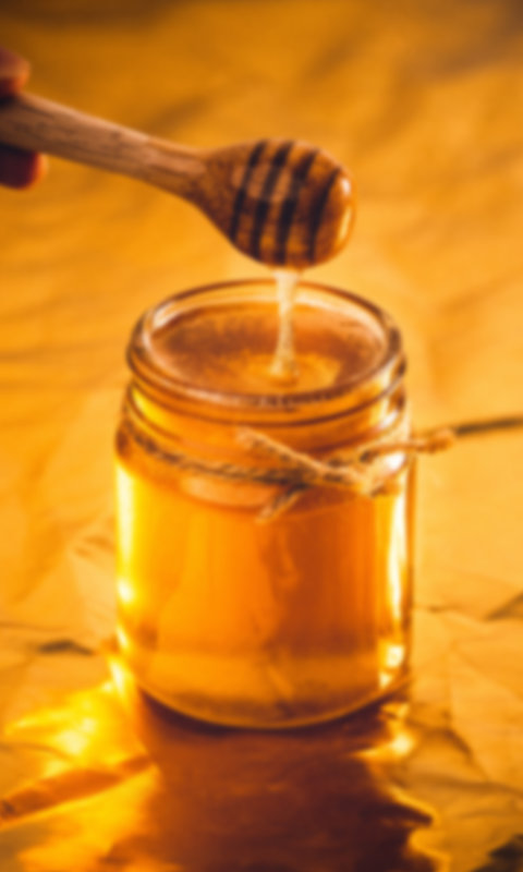Geöffnetes Honigglas mit hölzernem Honiglöffel